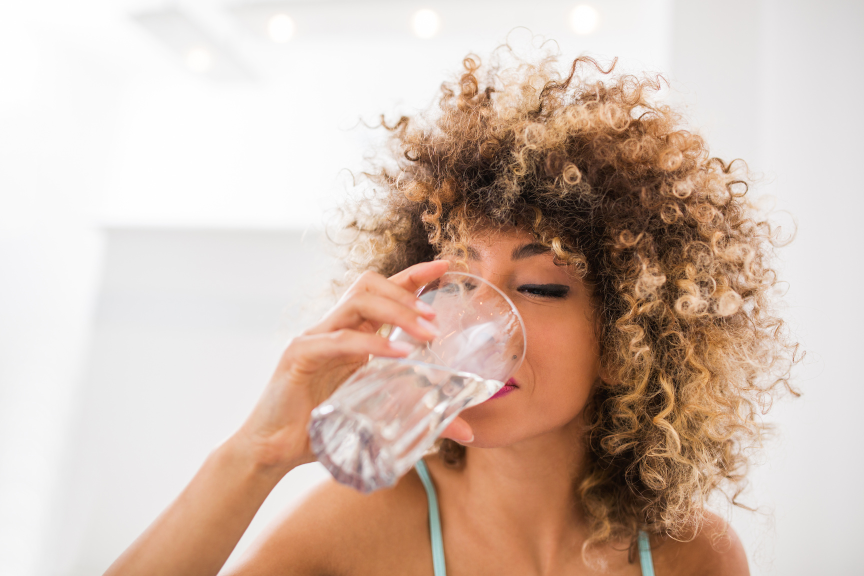 Thirsty African American woman drinking water.